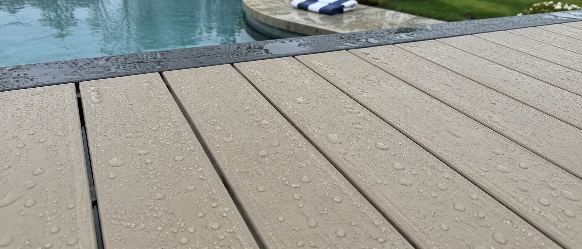 Water beading on pale PVC boards rather than soaking in, with a pool edge in the background